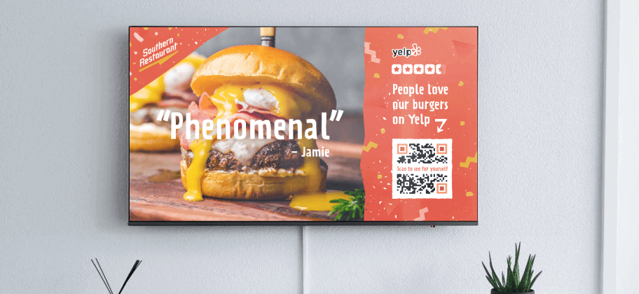 A wallmounted television with an image of a hamburger next to a QR Code for Yelp reviews.